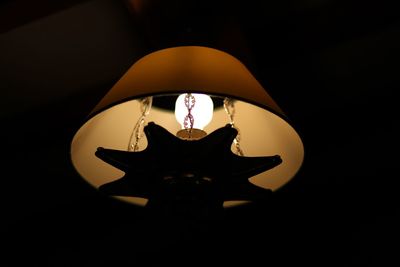 Low angle view of illuminated electric lamp in darkroom