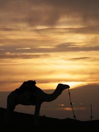 Silhouette statue against orange sky