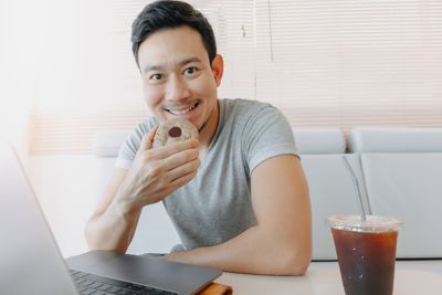 Portrait of young woman using laptop while sitting at home