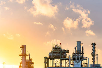 Low angle view of factory against sky during sunset