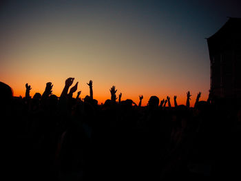 Silhouette crowd enjoying music concert against sky during sunset