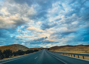 Surface level of road against cloudy sky