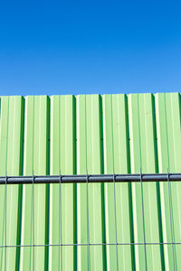 Full frame shot of green metal fence against blue background