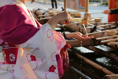 Woman pouring water from container to hand at japanese temple