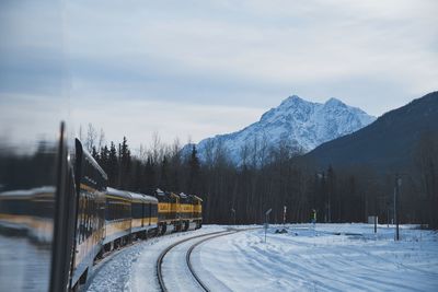 Train on railroad track against snowcapped mountains