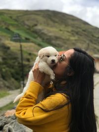 Woman kissing dog against mountains