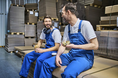 Two happy workers having lunch break in factory