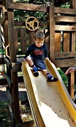 Portrait of boy sitting on slide at playground