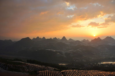 Scenic view of mountains against dramatic sky during sunset