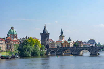 Bridge over river by buildings against sky in city