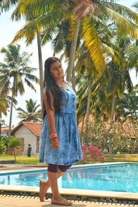 Full length portrait of young woman standing by swimming pool