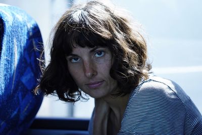 Close-up portrait of woman against window