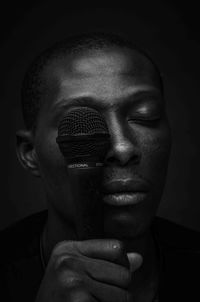 Close-up portrait of young man against black background