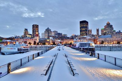 Snow covered bridge in city against sky