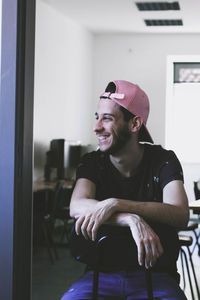 Smiling young man sitting on chair at home