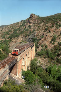 Passenger train at bridge in corse mountains in direction of ajaccio on corse island.