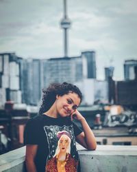 Smiling young woman standing against buildings in city