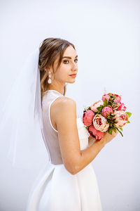 Young woman holding red rose against white background