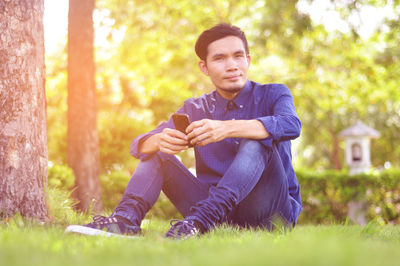 Young man using smart phone while sitting on grass