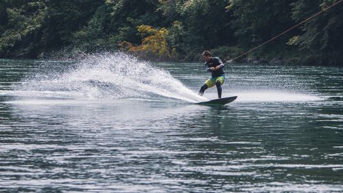 Man surfing on river against trees