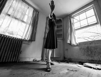 Rear view of woman standing by window in abandoned building