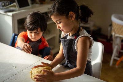 Two girls wearing grey aprons preparing dough