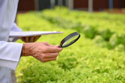 Midsection of man holding magnifying glass