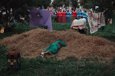 High angle view of woman sleeping on hay against people in background