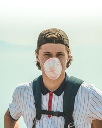 Portrait of teenage boy wearing mask against sky