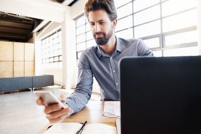 Young man using mobile phone while sitting on table