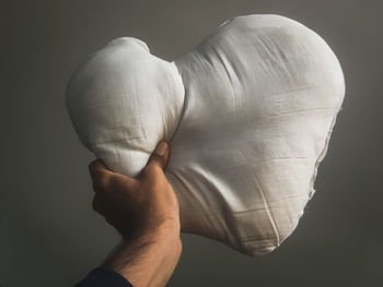 Close-up of man holding heart shape over white background