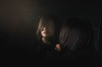 Close-up of young woman against black background
