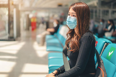 Woman wearing mask while sitting at airport