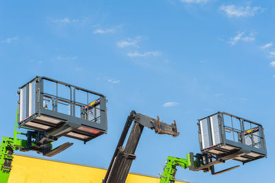 Low angle view lifting platforms against sky