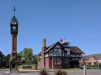 Clock tower amidst buildings against clear blue sky