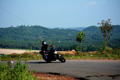 Man riding motorcycle on road against sky