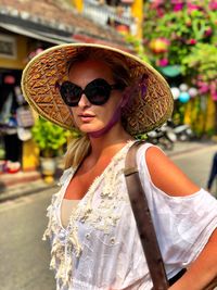 Portrait of woman wearing sunglasses standing on road