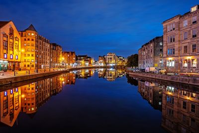 Reflection of illuminated buildings in lake against sky at night