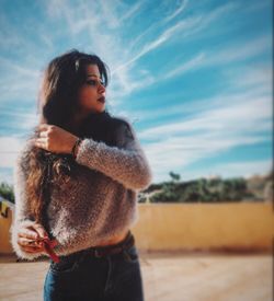 Young woman looking away against sky