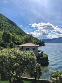 House by lake and tree against sky