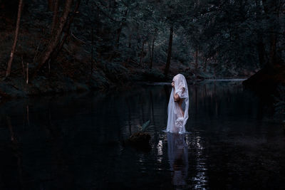 Woman standing by lake in forest