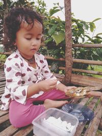 Girl looking away while sitting on wood