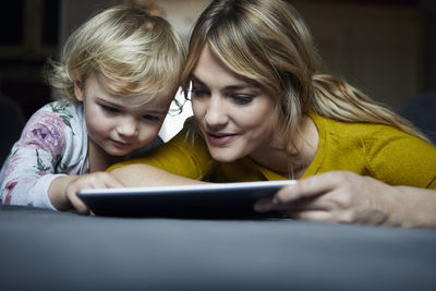 Portrait of mother and little daughter using tablet at home
