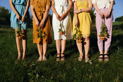 Low section of women standing on grassy field