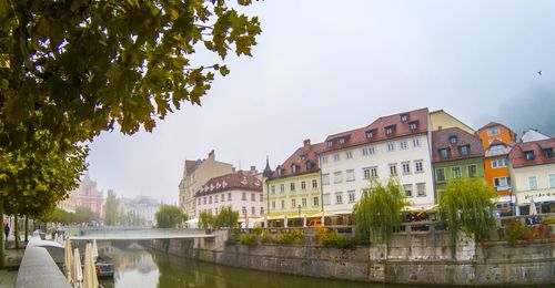 Buildings by river against sky in city