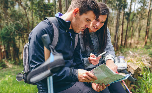 Young couple sitting on land in forest