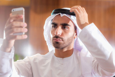 Close-up of man in traditional clothing taking selfie over smart phone