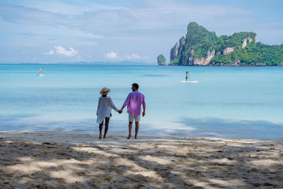 Rear view of people on beach against sky