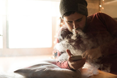 Portrait of young man using smart phone at home