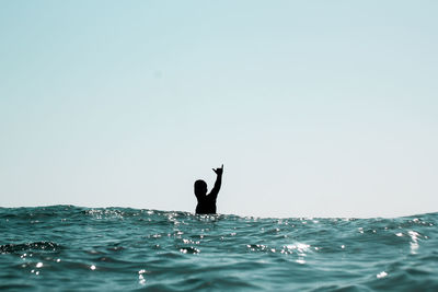 Man surfing in sea against clear sky